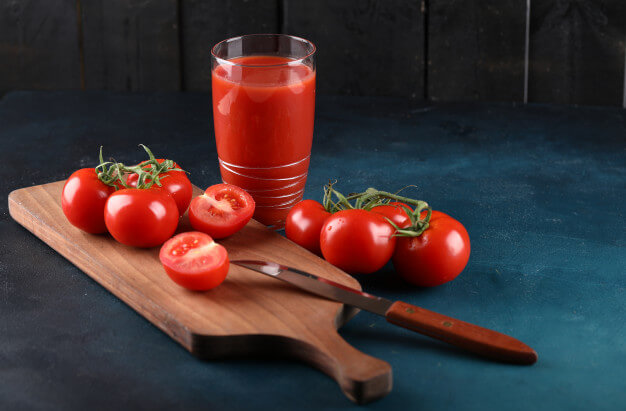 red tomatoes glass juice wooden board with knife blue background 114579 5117