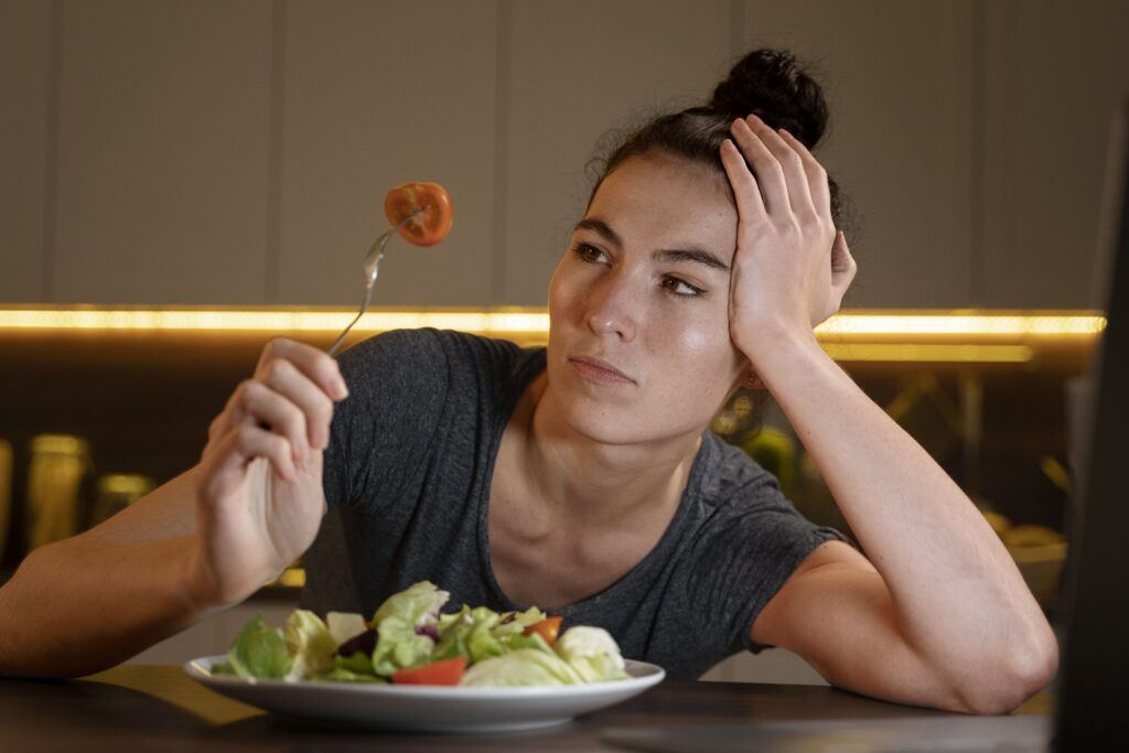 Mulher frustrada olhando para salada, pensando por que não emagrece mesmo fazendo dieta